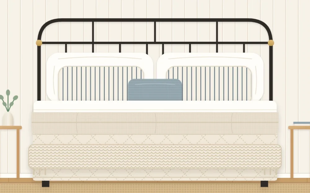 Made farmhouse bed seen from the foot with white sheets, an oat duvet folded back, a pale quilt, a chunky knit throw and layered pillows
