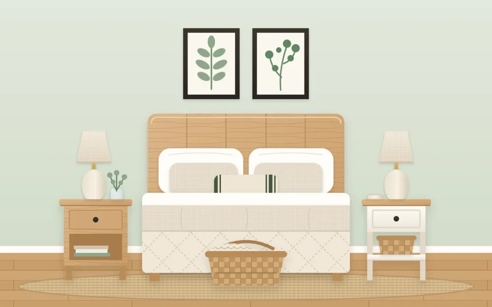 Farmhouse bedroom with a wooden headboard, cream and oat bedding, two nightstands with lamps, a basket at the foot and two botanical prints