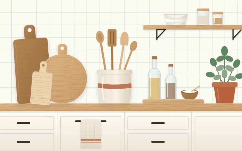 Kitchen counter corner with three leaning wooden cutting boards, a stoneware crock of utensils, a small tray of bottles and a potted herb