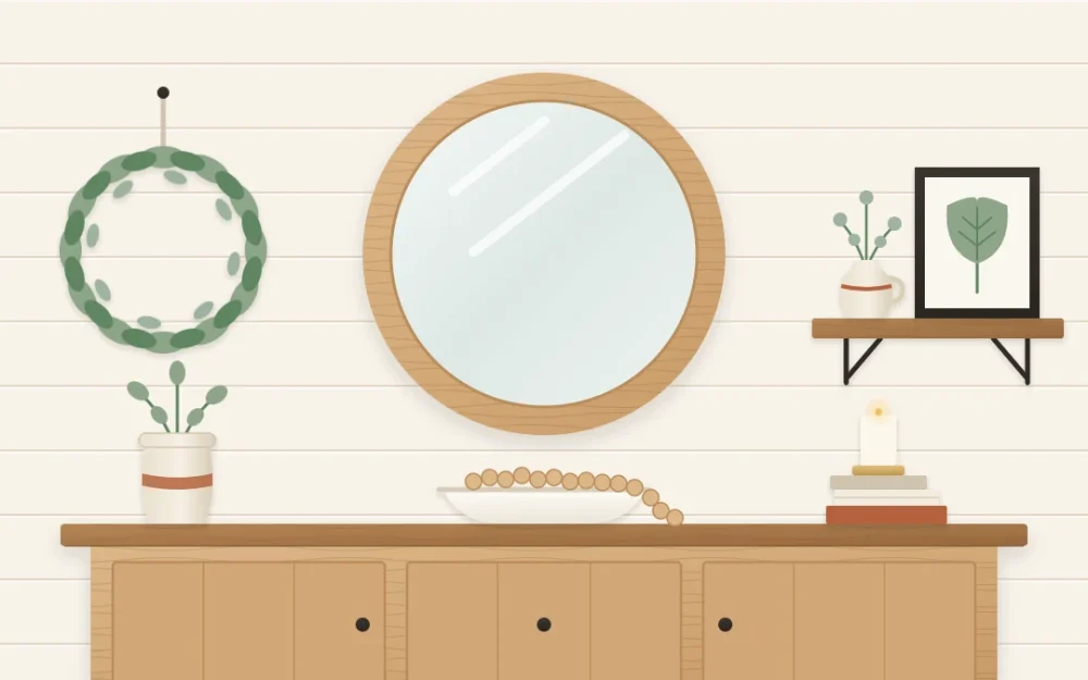 Warm white plank wall above a wooden console with a large round wood-framed mirror, a greenery wreath and a short shelf holding a jug and leaf print